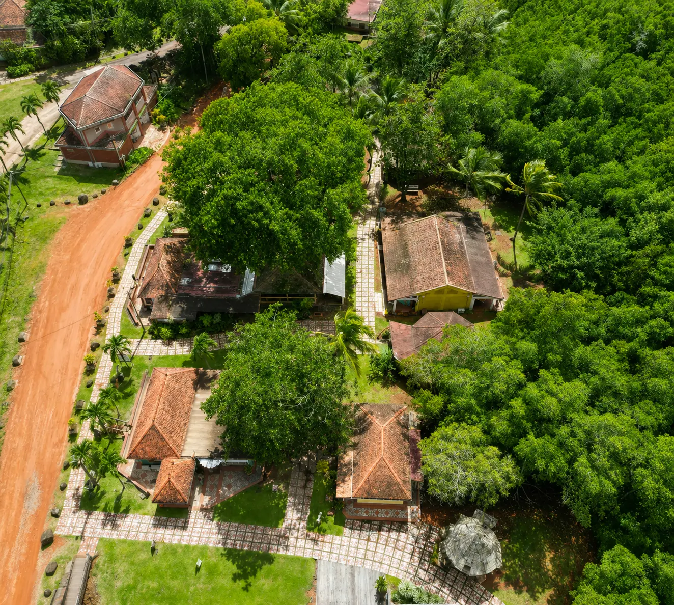 Vue aérienne du Village de la Poterie aux Trois-Îlets : toits en tuiles rouges, ateliers artisanaux et forêt dense.