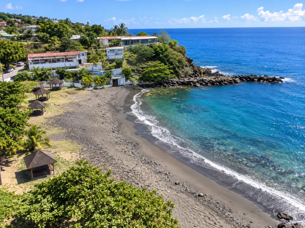 Plage de Rocroy en Guadeloupe vue du ciel, plage de sable noir, eaux turquoise et côte tropicale.