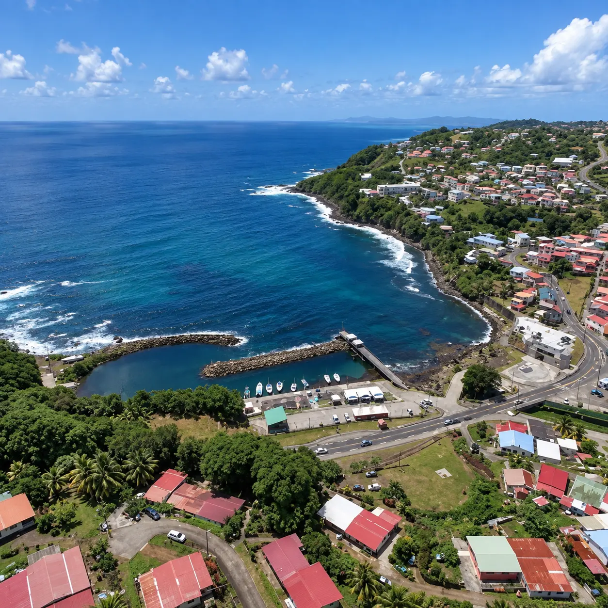 Côte du Marigot en Martinique vue du ciel, avec sa baie, son port, son littoral rocheux, ses maisons colorées et les eaux turquoise de la mer des Caraïbes.