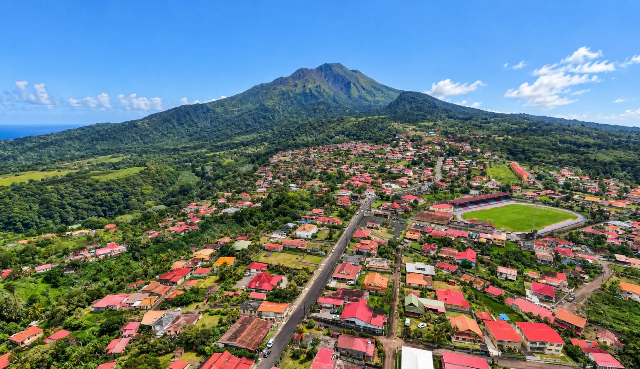 Morne-Rouge en Martinique vu du ciel, avec son bourg entouré de végétation tropicale au pied de la montagne Pelée sous un ciel dégagé.