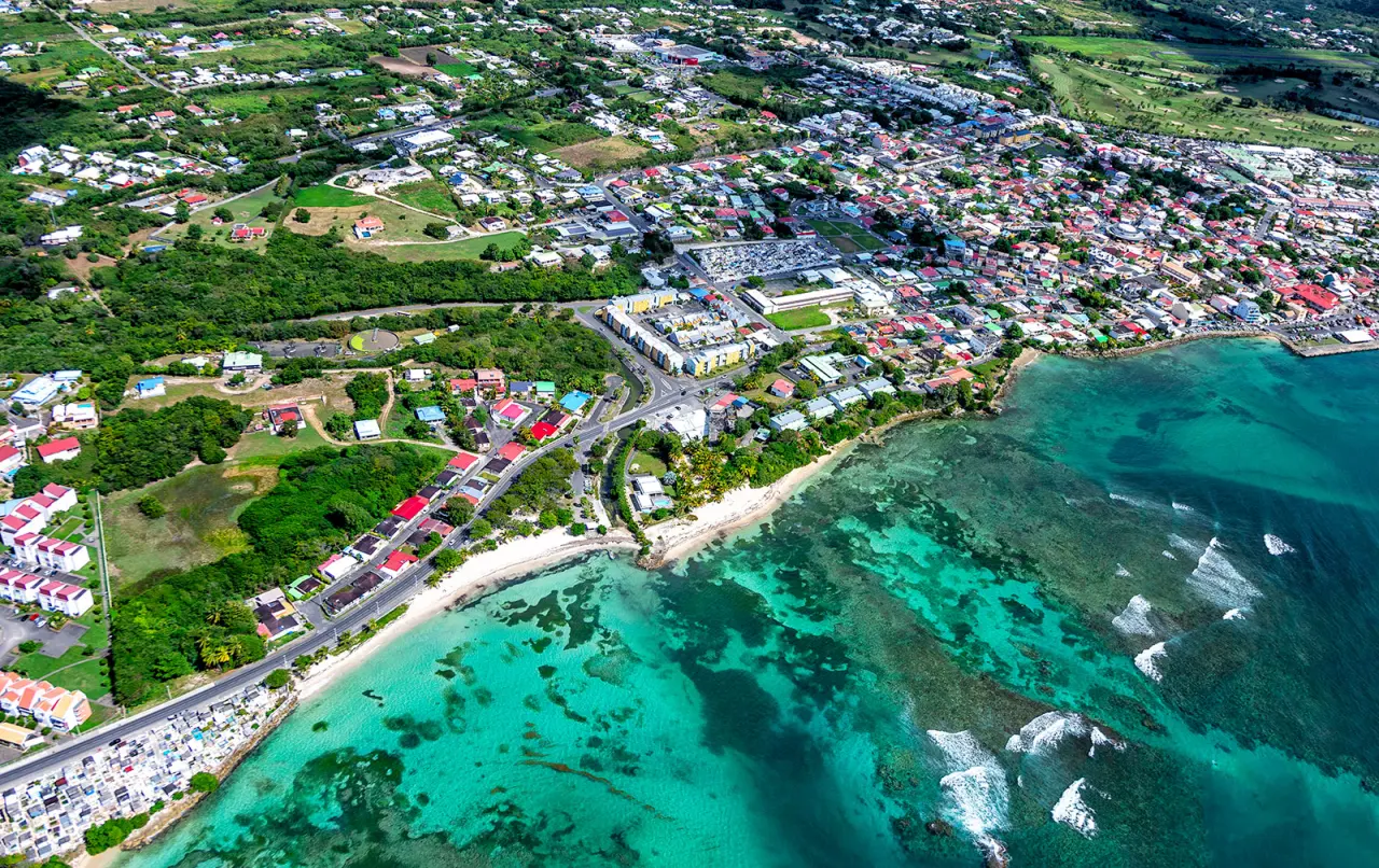 Vue aérienne de Saint-François en Guadeloupe : littoral rocheux, barrière de corail, eau turquoise et bourg urbain.