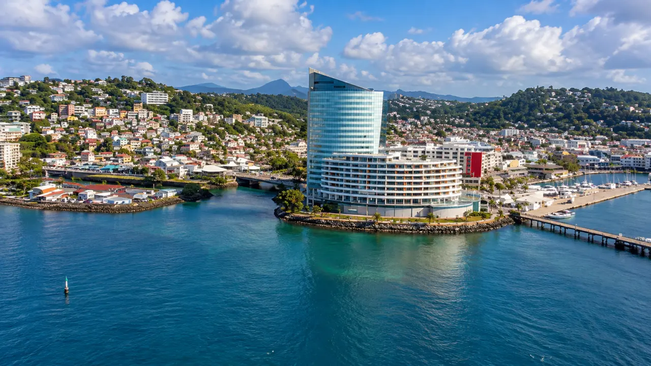 Vue aérienne de Fort-de-France en Martinique, avec baie, marina, quartier des Trois-Îlets et paysage urbain entouré de collines verdoyantes.