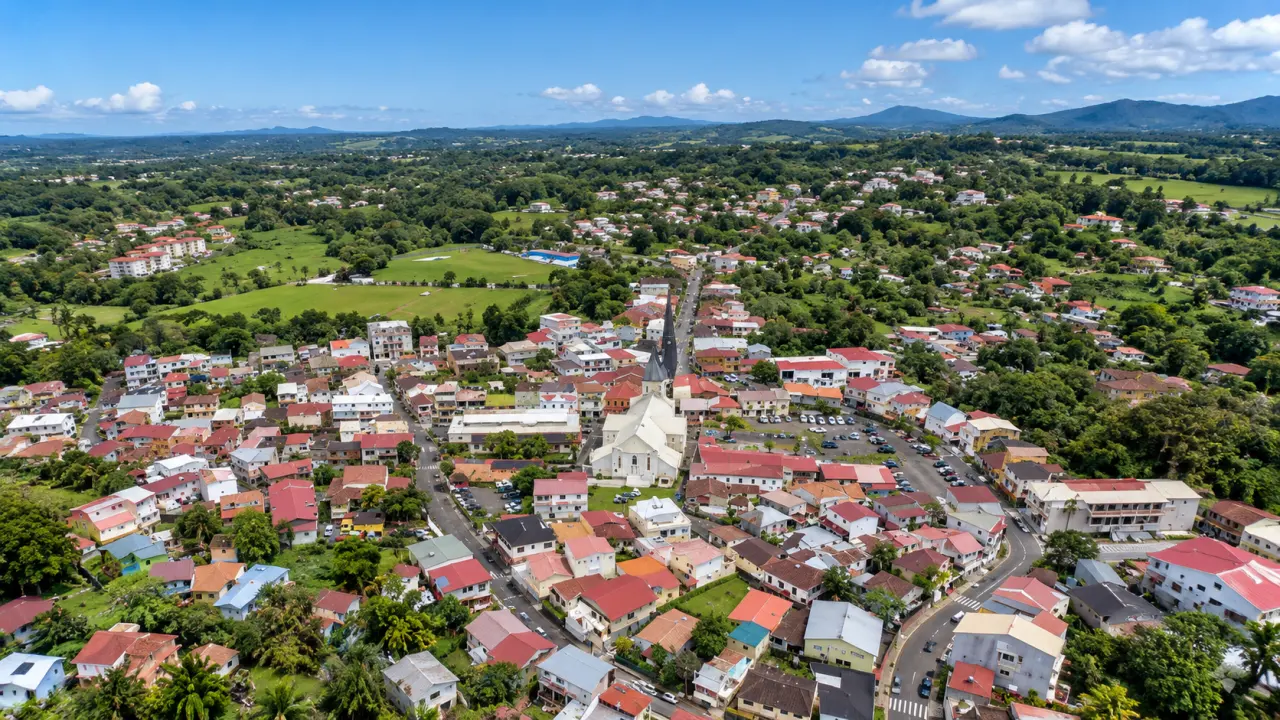 Vue aérienne de Fort-de-France en Martinique, ville tropicale entourée de végétation, quartiers résidentiels, église, collines et montagnes en arrière-plan.