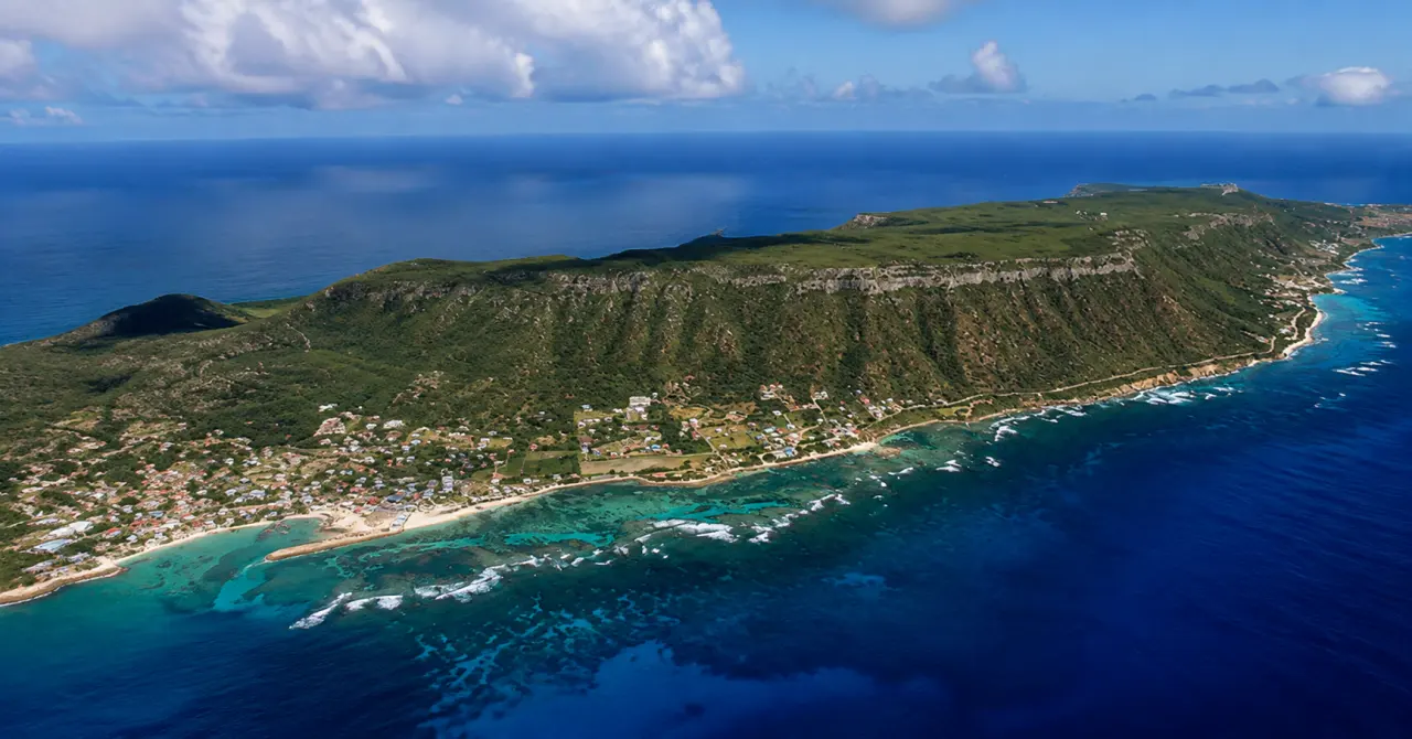 Vue aérienne de La Désirade en Guadeloupe, avec ses falaises verdoyantes, son littoral turquoise et son village côtier.