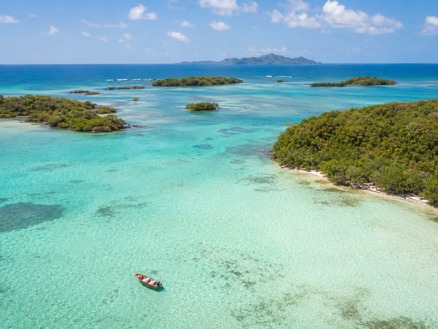 Vue aérienne des îlets du François en Martinique : lagon turquoise transparent, petite yole et végétation tropicale.
