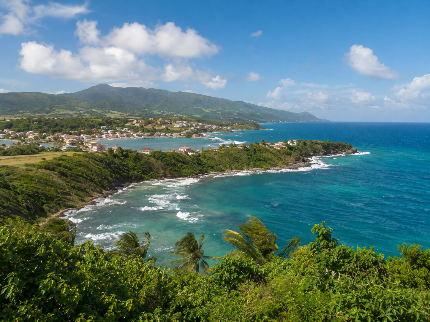 Littoral sauvage de La Trinité en Martinique : baie d'eau turquoise, vagues blanches et collines verdoyantes au loin.