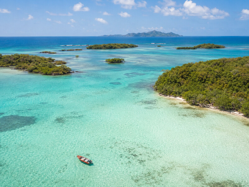 Vue aérienne des îlets du François en Martinique : lagon turquoise transparent, petite yole et végétation tropicale.