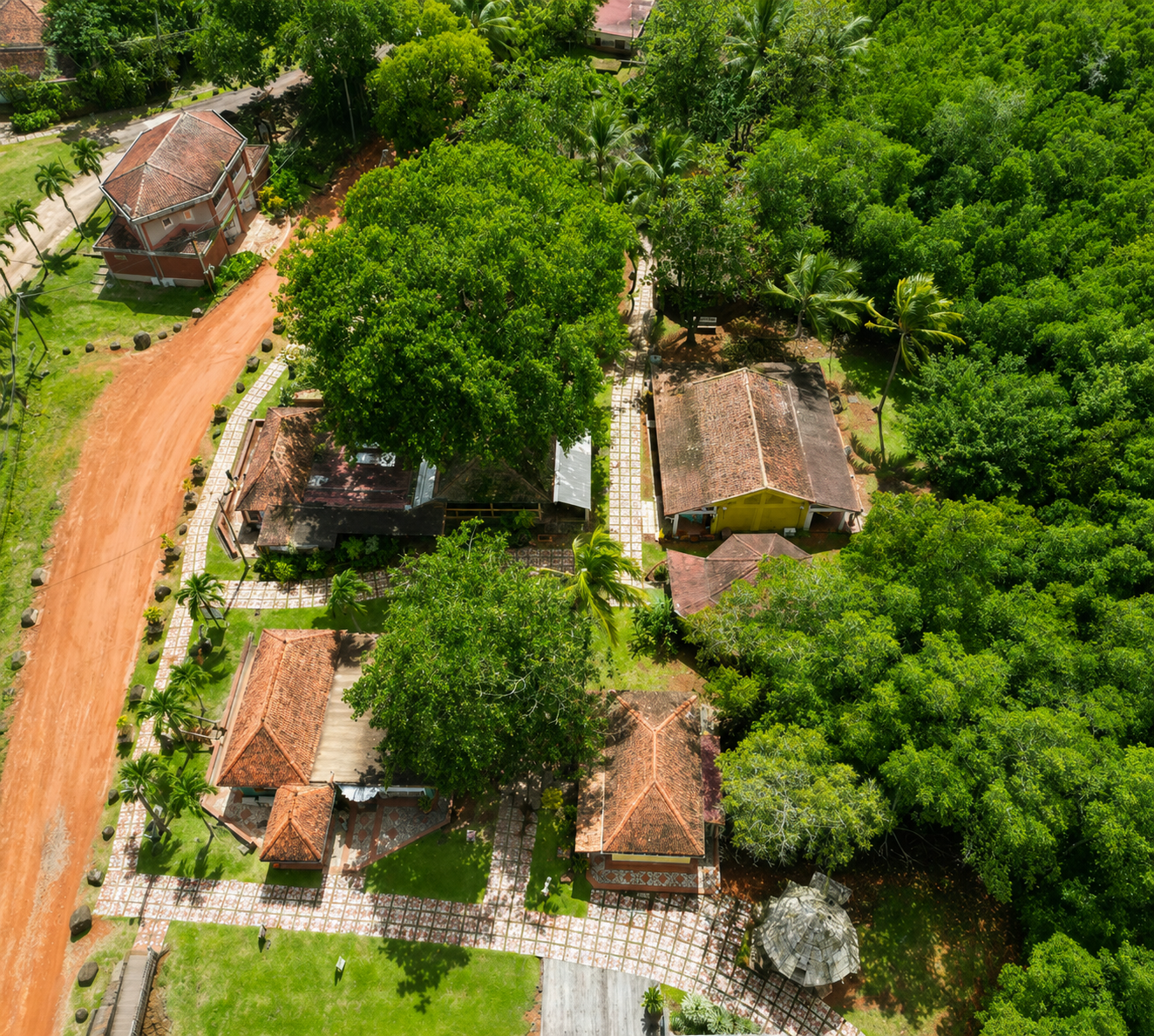 Vue aérienne du Village de la Poterie aux Trois-Îlets : toits en tuiles rouges, ateliers artisanaux et forêt dense. 
