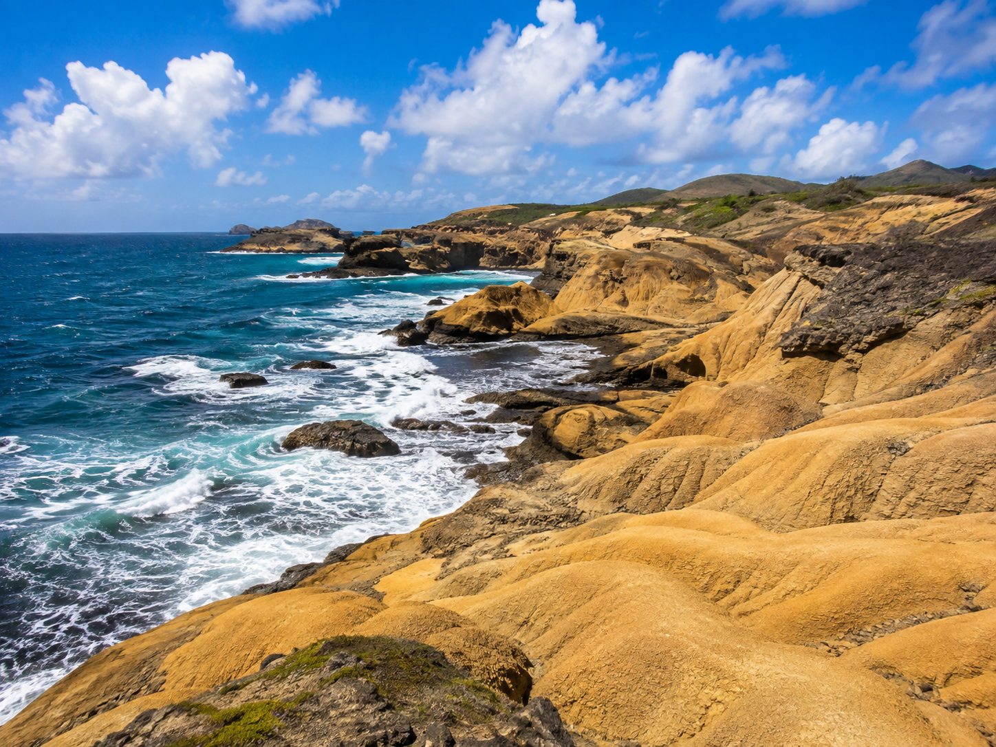 Falaises dorées et désertiques de la Savane des Pétrifications à Sainte-Anne en Martinique, face à une mer bleue agitée.