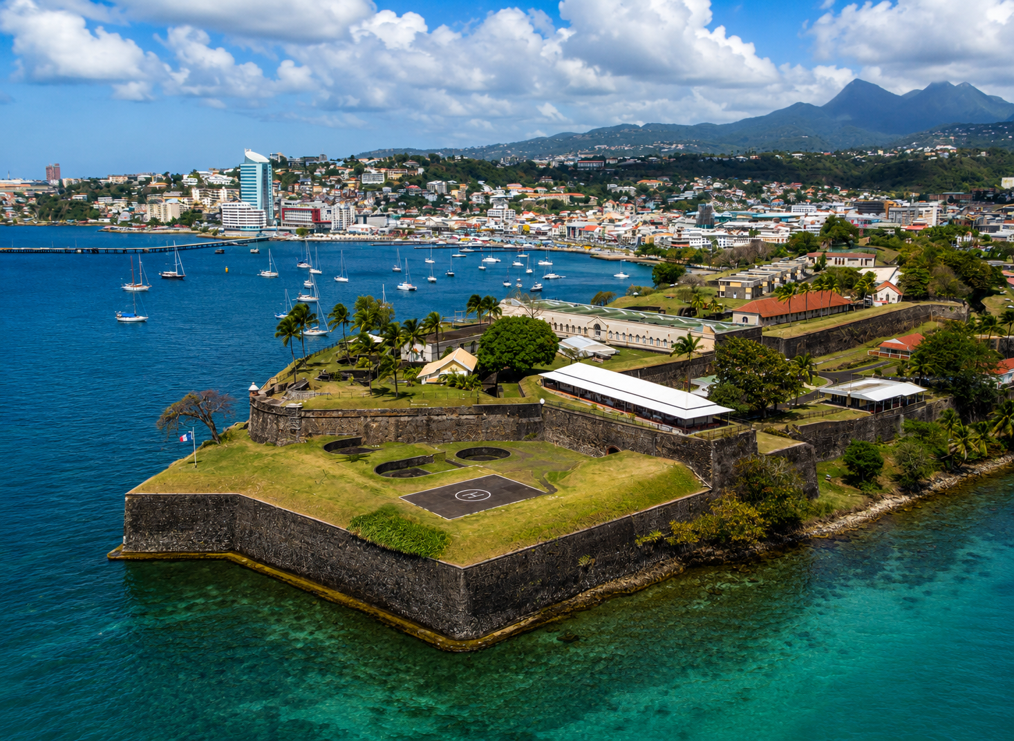 Vue aérienne du Fort Saint-Louis à Fort-de-France en Martinique : fortifications entourées d'eau turquoise et ville au loin. 