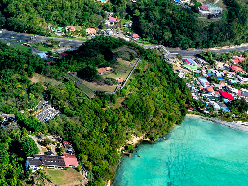 Vue aérienne du Fort Fleur d'Épée en Guadeloupe, sur une colline verdoyante bordant une mer turquoise et le littoral du Gosier.