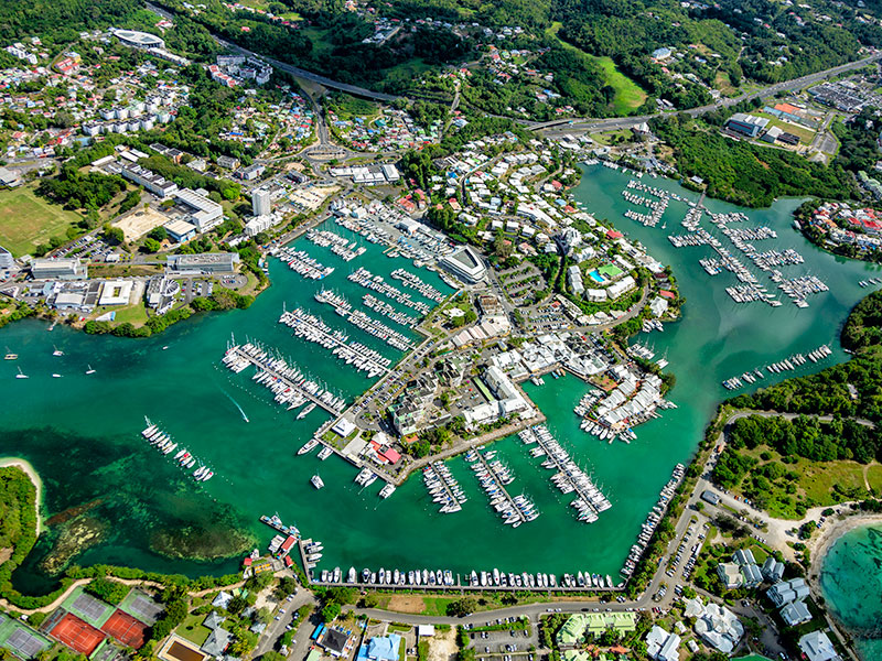 Vue aérienne de la marina de Bas-du-Fort en Guadeloupe : nombreux bateaux à quai dans des bassins d'eau verte et bâtiments.