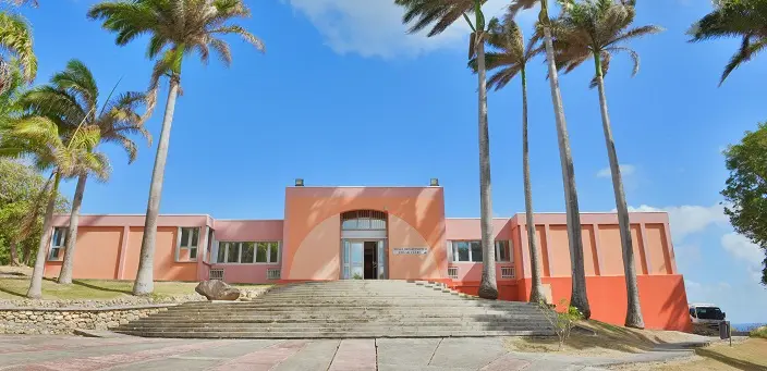 Facade avant du Musée Edgar Clerc au Moule en Guadeloupe avec des palmiers et ciel bleu.