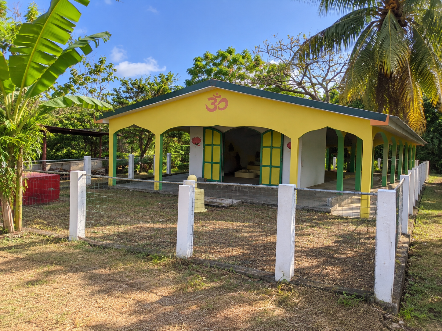 Temple hindou de Guadeloupe, sanctuaire jaune et vert orné du symbole Om au cœur d’une végétation tropicale.