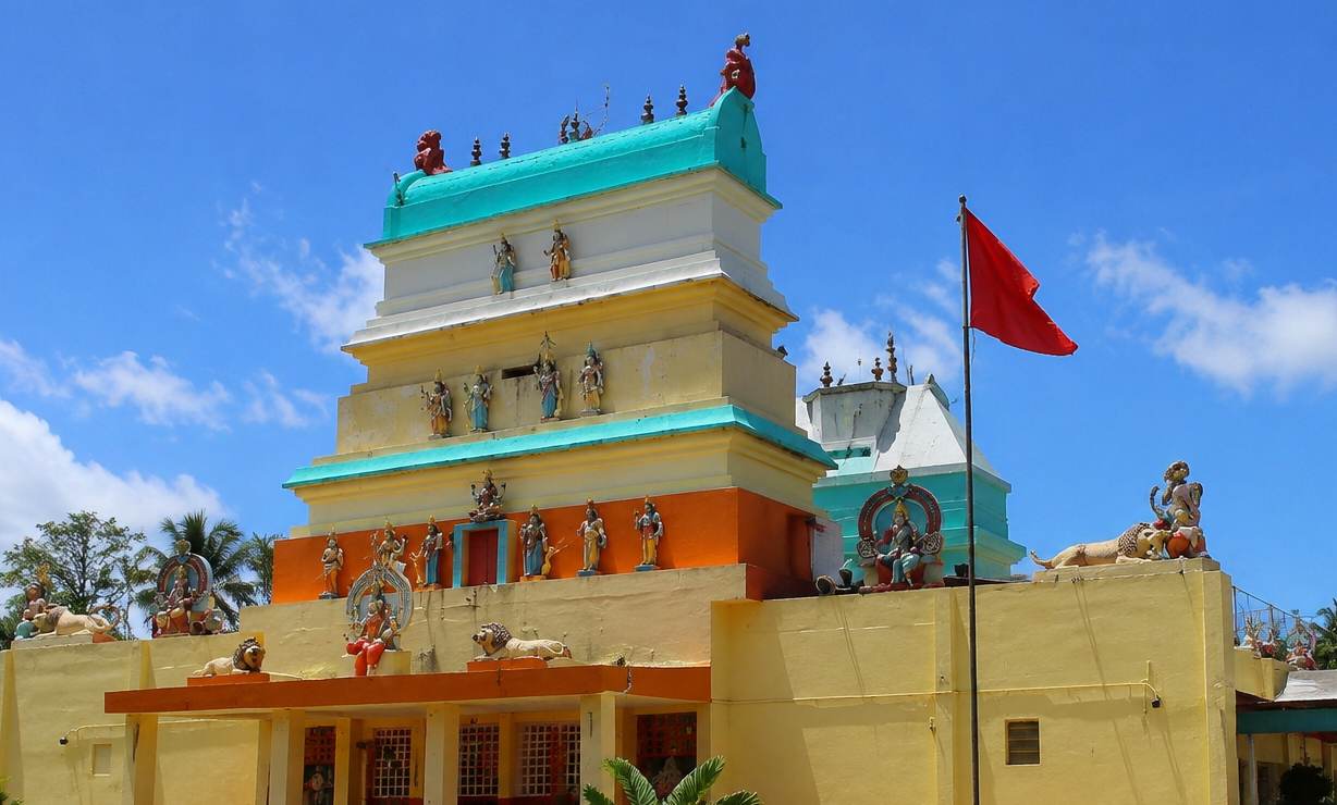 Le Temple hindou de Changy en Guadeloupe, une structure colorée ornée de statues de divinités, avec un drapeau rouge, sous un ciel bleu.