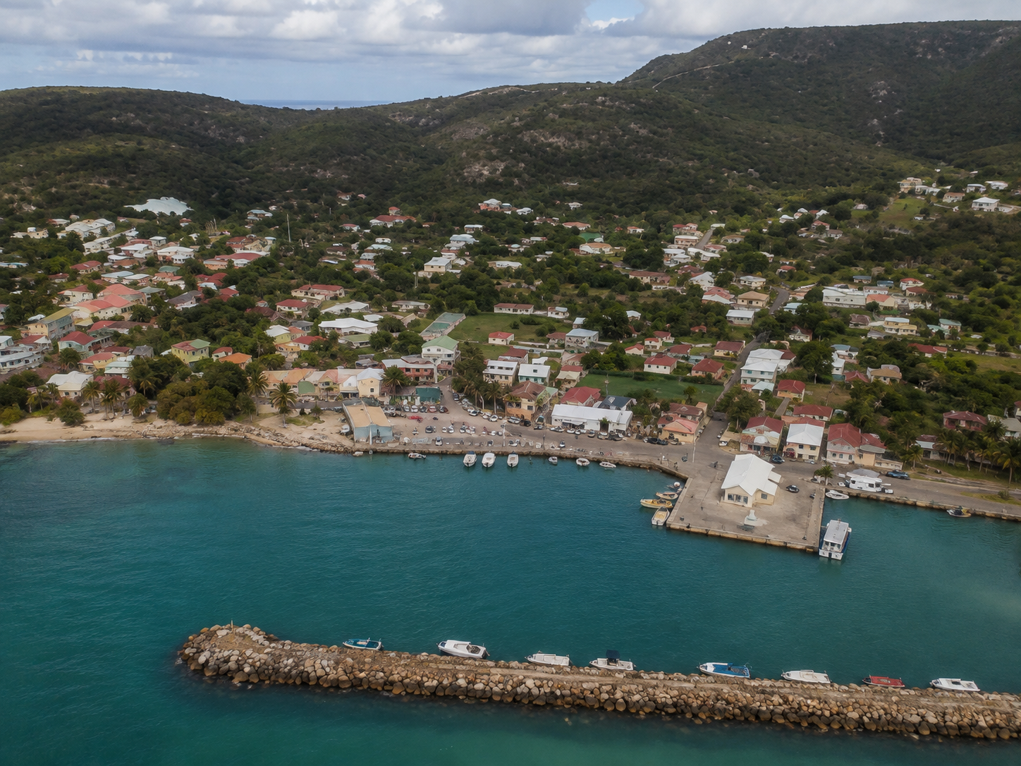 Vue aérienne du bourg de Beauséjour à La Désirade en Guadeloupe, avec le port, les bateaux et les collines verdoyantes