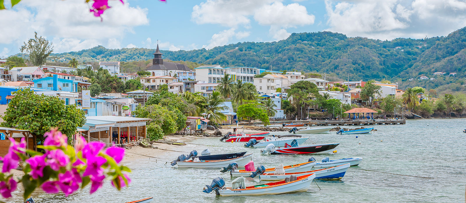 Bateaux de pêche amarrés sur le littoral du bourg de Sainte-Luce en Martinique avec l'église en arrière-plan.