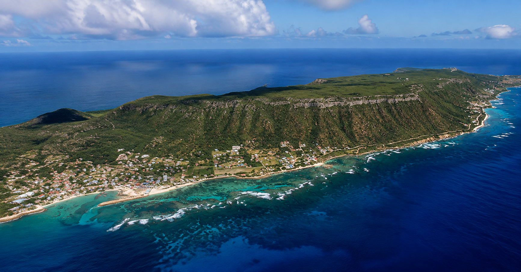 Vue aérienne de La Désirade en Guadeloupe, avec ses falaises verdoyantes, son littoral turquoise et son village côtier.